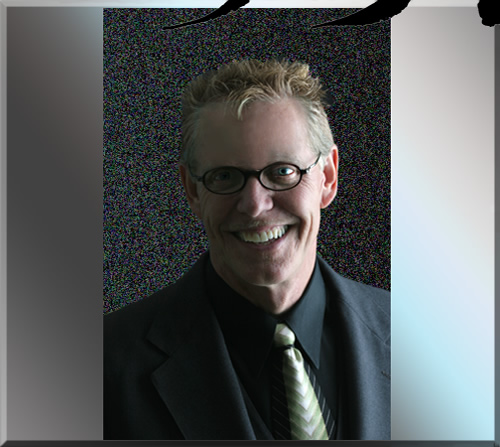 Photo of Jerry Michelsen in a grey suit, wearing glasses and a big smile