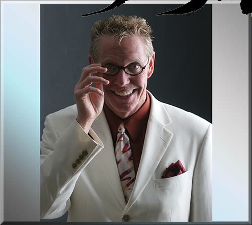 Photo of Jerry Michelsen in a white suit and smiling. His hand his about to remove his glasses.